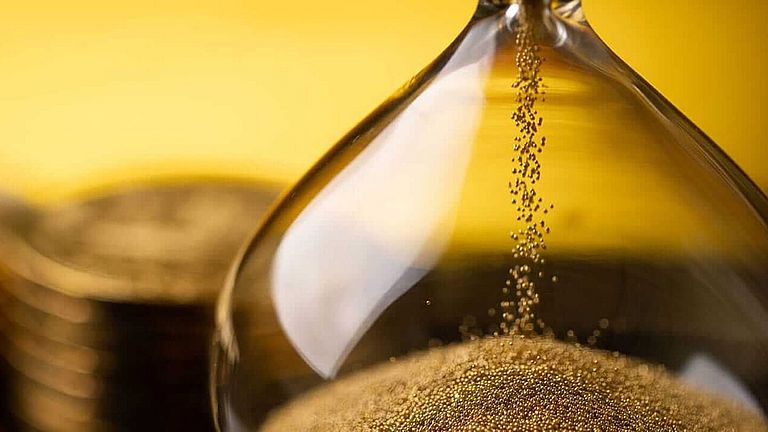Sanduhr mit Geld im Hintergrund für SEPA Instant Payments